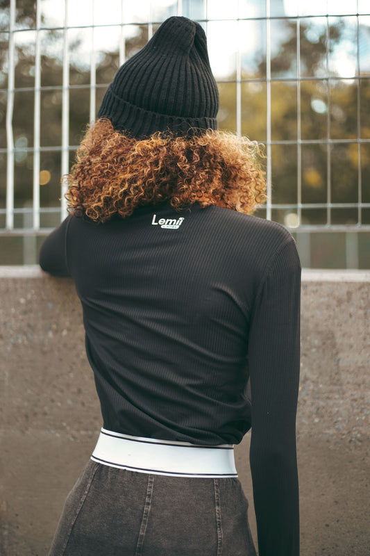 Lemii Label - Person wearing a black athletic long-sleeve shirt with 'Lemii Label' branding, standing against a wall.