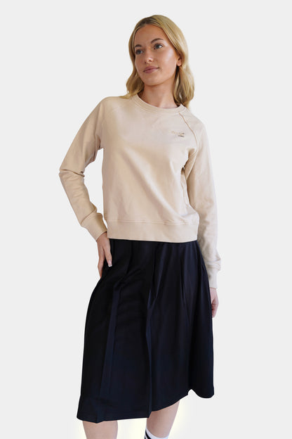 Lemii Label - Woman wearing a  beige crew sweater, short athletic black skirt - white background. 