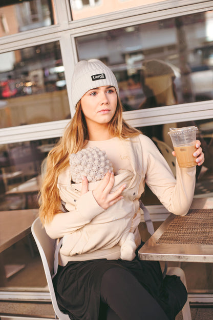 lemii Label - woman drinking coffee - holding a baby - wearing hat and sweater